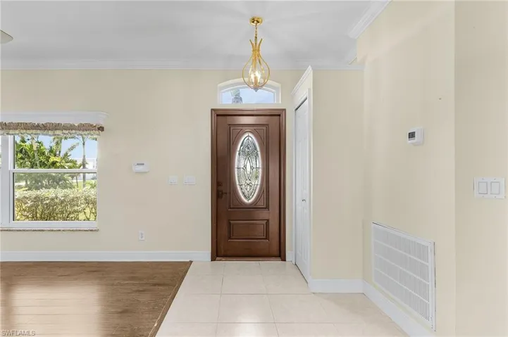 Foyer entrance with baseboards, ornamental molding, light tile patterned floors, and a chandelier