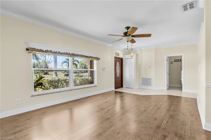 Unfurnished room with light wood-style flooring, a ceiling fan, ornamental molding, and baseboards