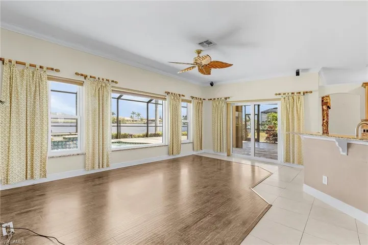 Empty room with a ceiling fan, plenty of natural light, ornamental molding, a water view, and light wood-style floors