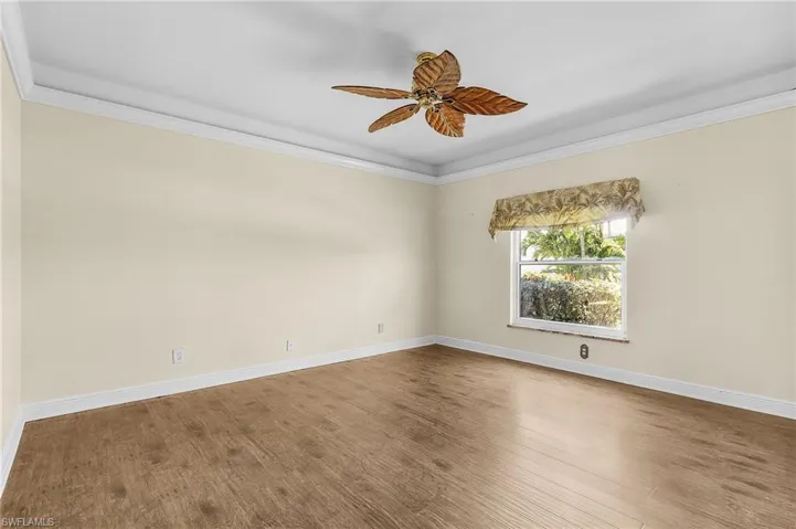 Spare room featuring wood finished floors, a ceiling fan, ornamental molding, and baseboards