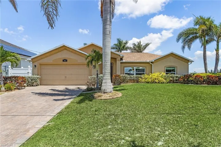 View of front of home featuring stucco siding, a front yard, decorative driveway, and a garage