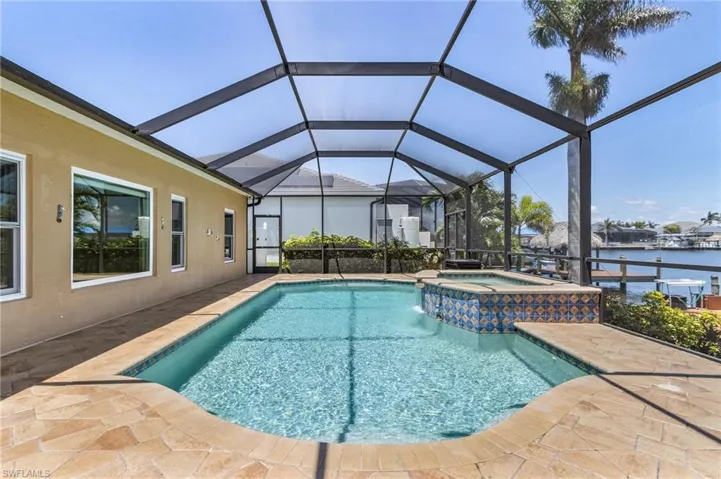 View of swimming pool featuring a patio area, a pool with connected hot tub, and a water view