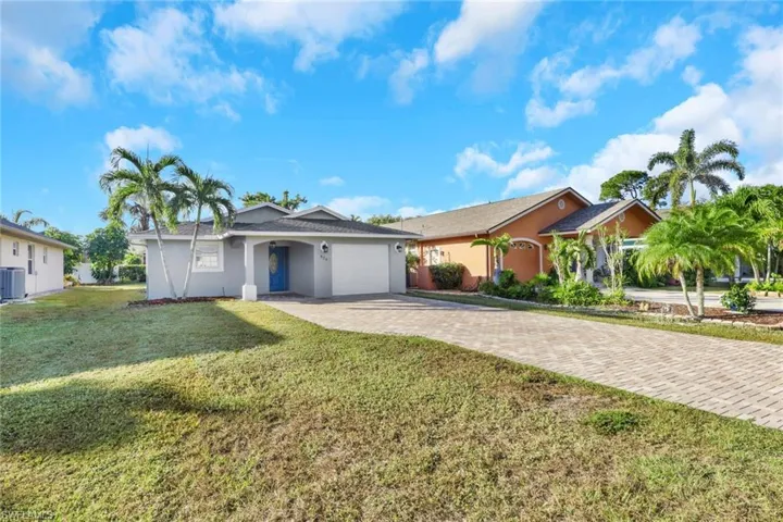 Ranch-style home with decorative driveway, stucco siding, a garage, and a front lawn