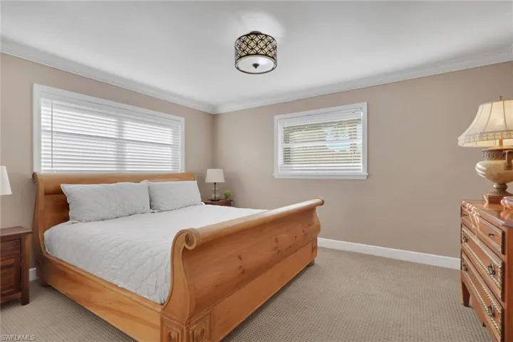 Bedroom with light carpet, crown molding, and multiple windows