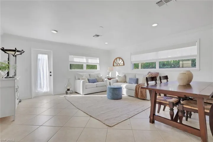 Living area with light tile patterned flooring, crown molding, and recessed lighting