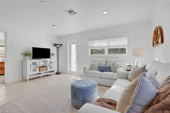 Living area featuring tile patterned floors, crown molding, and recessed lighting