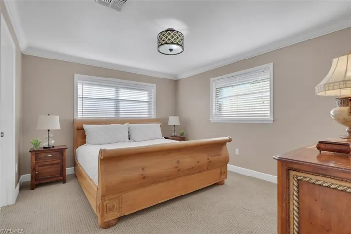 Bedroom with light colored carpet and ornamental molding