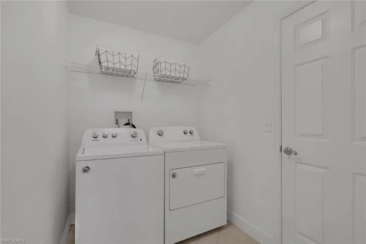 Laundry area featuring washing machine and dryer and light tile patterned floors