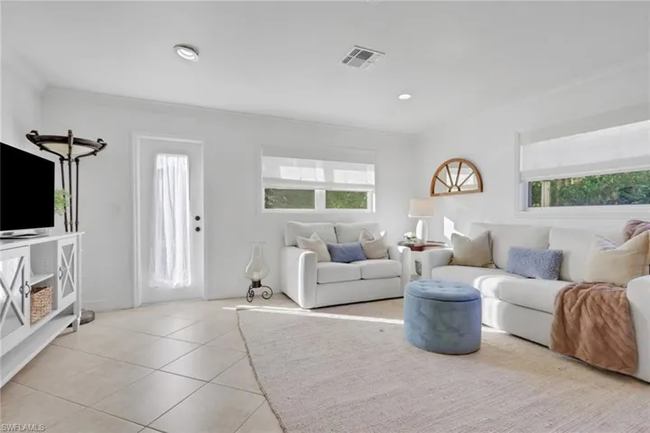 Tiled living area with plenty of natural light, crown molding, and recessed lighting