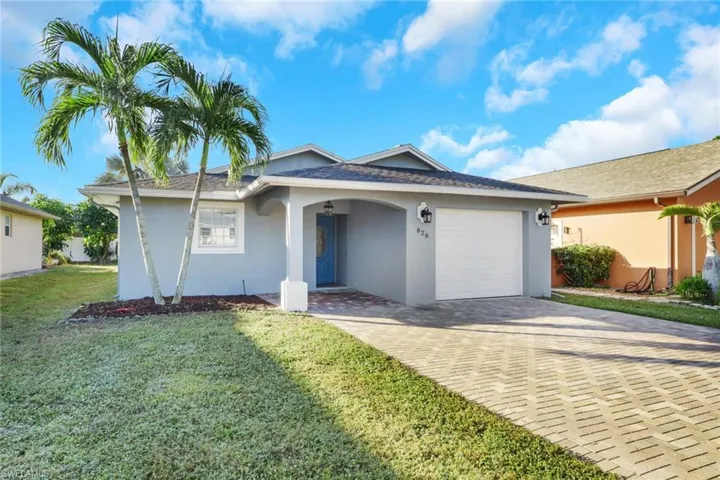 Ranch-style home featuring stucco siding, a garage, a front yard, and decorative driveway