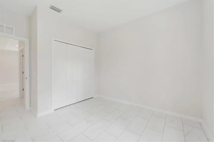 Unfurnished bedroom featuring light marble finish floors and a closet