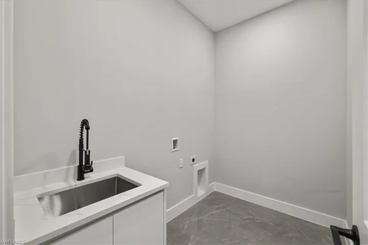 Washroom with dark marble finish flooring, hookup for a washing machine, and electric dryer hookup