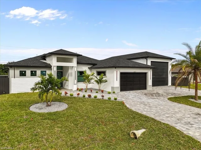 Prairie-style home with a garage, decorative driveway, a front yard, stucco siding, and a shingled roof