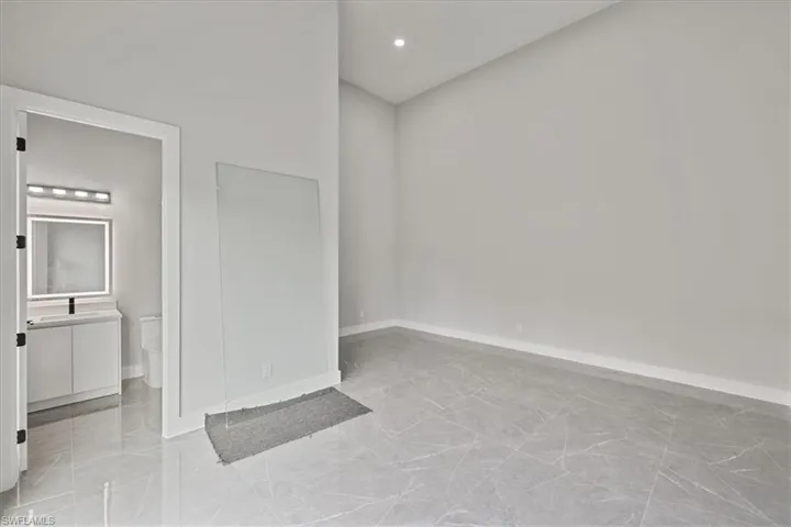 Unfurnished bedroom with recessed lighting, light marble finish floors, and ensuite bath