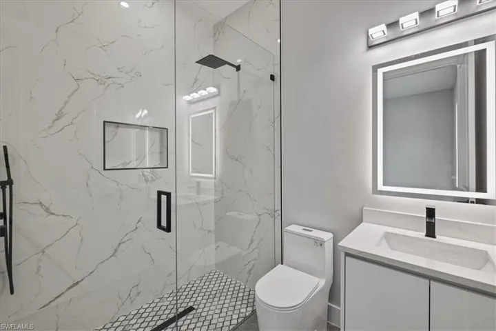Bathroom featuring vanity and a marble finish shower