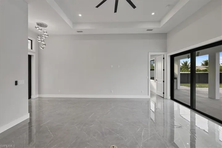 Unfurnished room featuring plenty of natural light, light marble finish flooring, a raised ceiling, ceiling fan, and recessed lighting