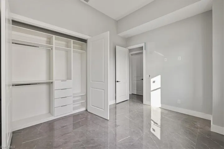 Unfurnished bedroom featuring light marble finish flooring and a closet