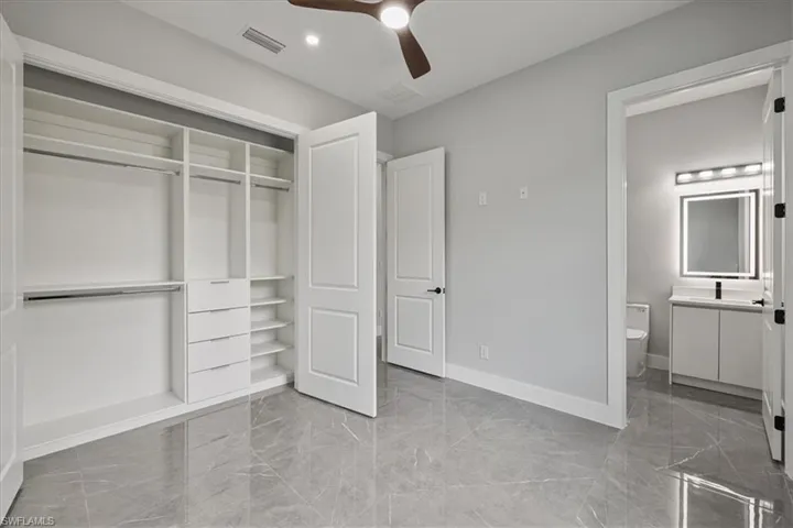 Unfurnished bedroom with light marble finish flooring, a closet, and a ceiling fan