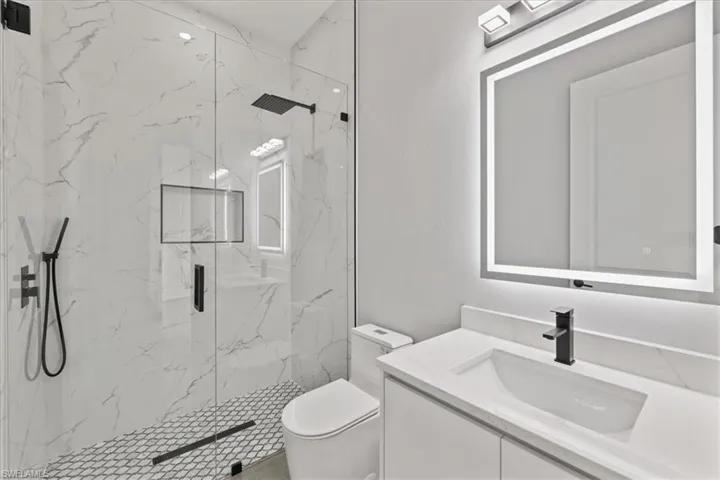 Bathroom with vanity and a marble finish shower