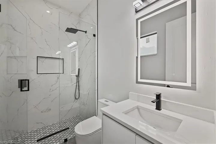 Full bath featuring vanity and a marble finish shower