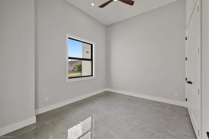 Unfurnished room featuring light marble finish flooring and ceiling fan