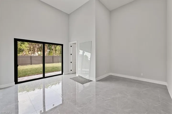 Empty room featuring a towering ceiling and light marble finish flooring