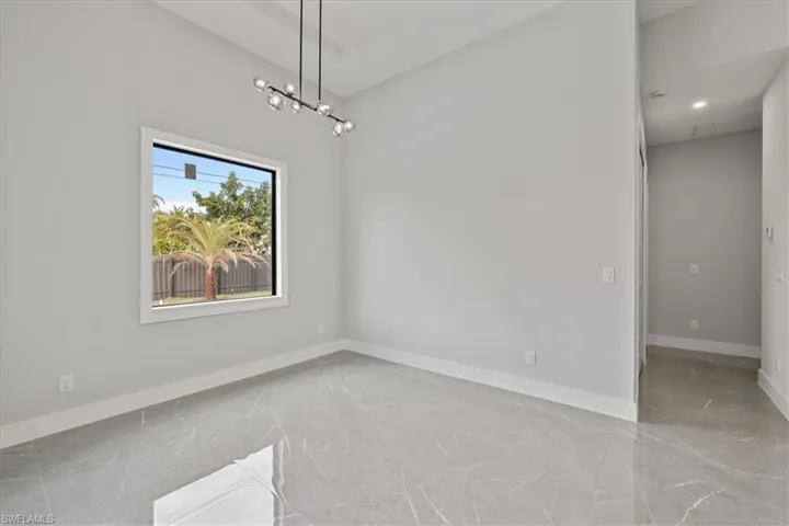 Unfurnished dining area featuring light marble finish flooring and a chandelier