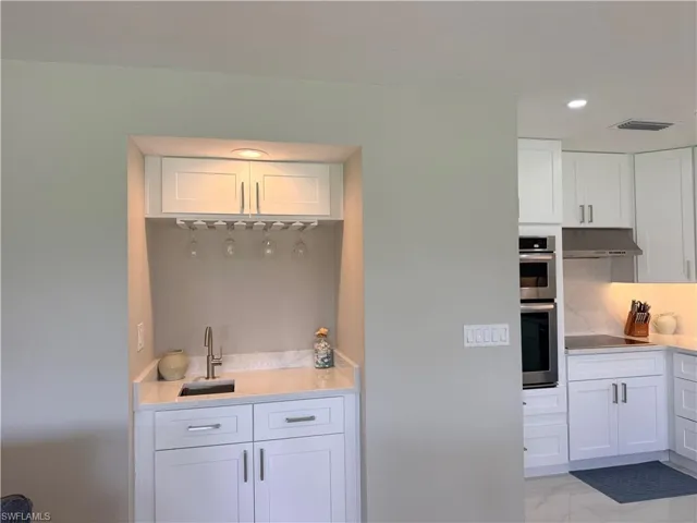 Kitchen with white cabinetry, light stone countertops, recessed lighting, stainless steel double oven, and black electric cooktop