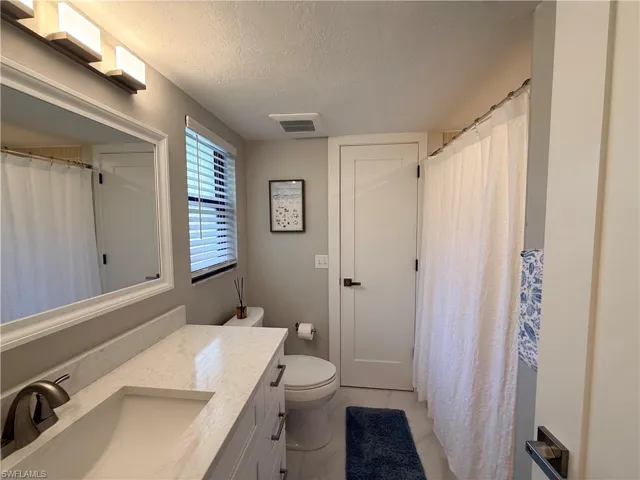 Bathroom featuring a textured ceiling, vanity, and a shower with shower curtain