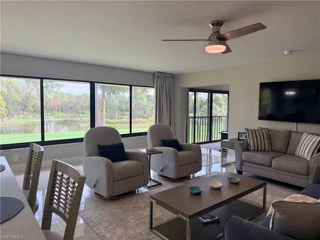 Tiled living area with a ceiling fan, a water view, and view of scattered trees