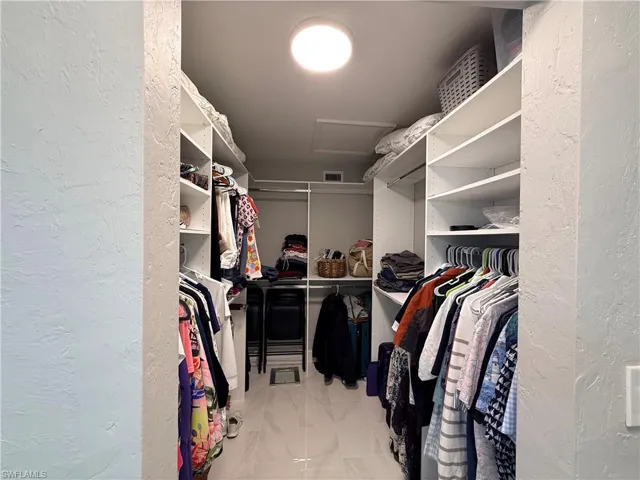 Walk in closet with attic access and light marble finish floors
