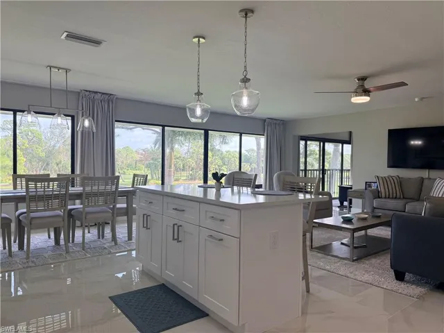 Kitchen featuring open floor plan, a kitchen breakfast bar, a center island, light stone countertops, and hanging light fixtures