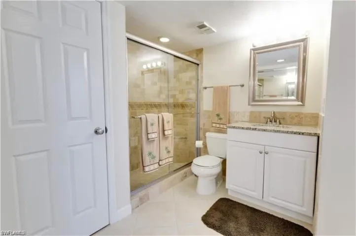 Bathroom featuring vanity, toilet, tile patterned flooring, and walk in shower