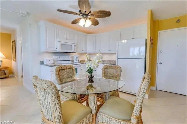 Kitchen featuring light tile patterned flooring, ceiling fan, white appliances, and white cabinets