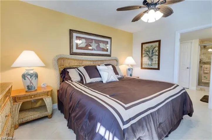Bedroom with ensuite bathroom, ceiling fan, and light tile patterned floors