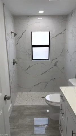 Bathroom featuring vanity, a marble finish shower, and recessed lighting