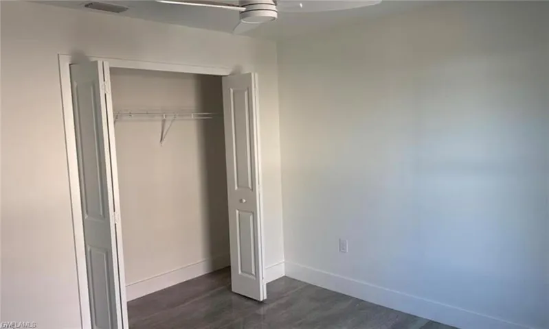 Unfurnished bedroom with a closet, ceiling fan, and dark wood-style flooring