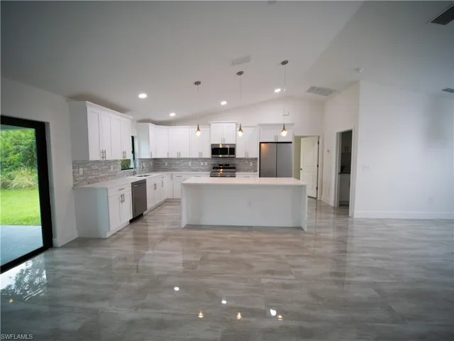 Kitchen with a kitchen island, tasteful backsplash, lofted ceiling, hanging light fixtures, and open floor plan