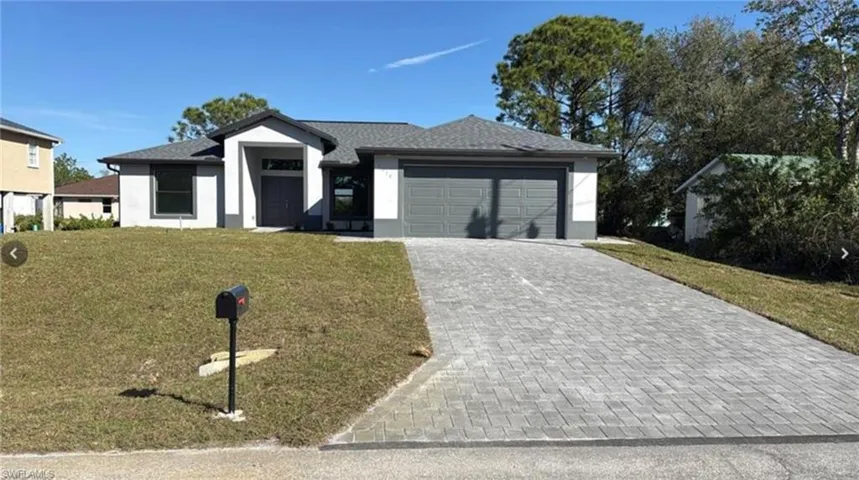 View of front facade with a front yard, decorative driveway, stucco siding, an attached garage, and a shingled roof
