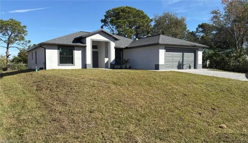 Ranch-style home featuring stucco siding, a front yard, driveway, and an attached garage
