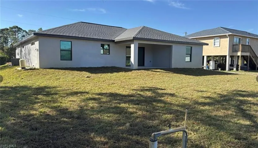 Back of house featuring stucco siding, a yard, a patio area, and roof with shingles