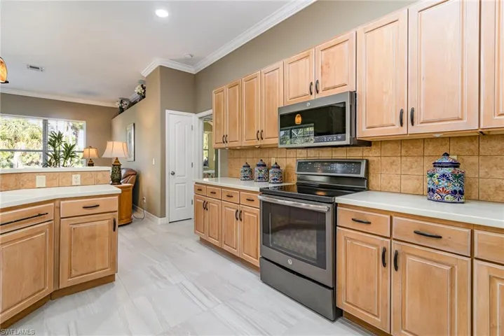 Kitchen featuring sink, crown molding, tasteful backsplash, light brown cabinets, and appliances with stainless steel finishes