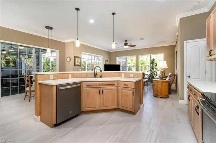 Kitchen with stainless steel appliances, sink, hanging light fixtures, and a center island with sink