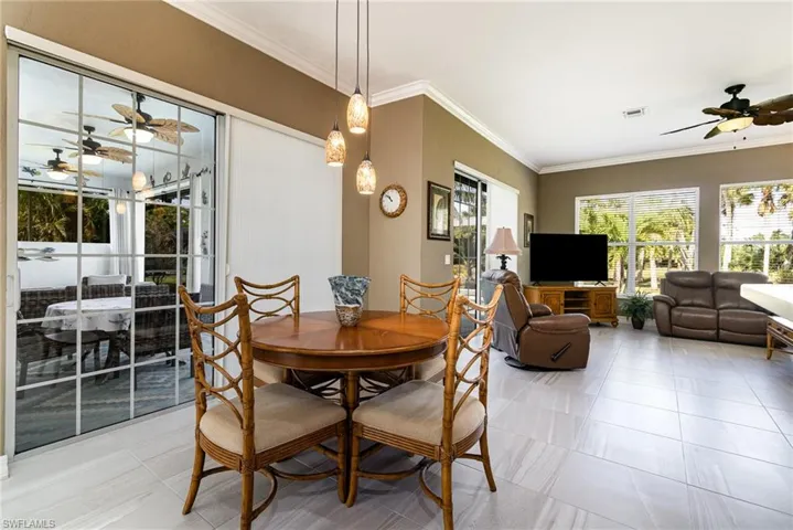 Tiled dining room with crown molding and ceiling fan
