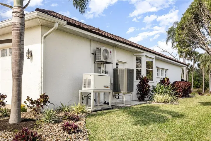 Back of property featuring ac unit, cooling unit, generator and  lawn