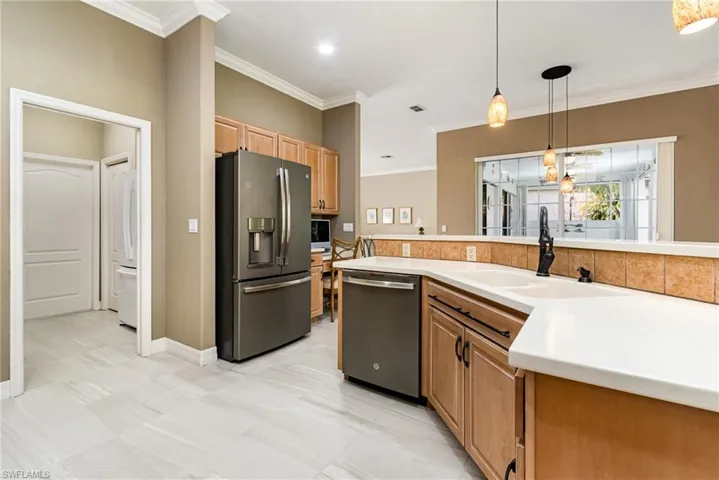 Kitchen with stainless steel appliances, crown molding, sink, and decorative light fixtures