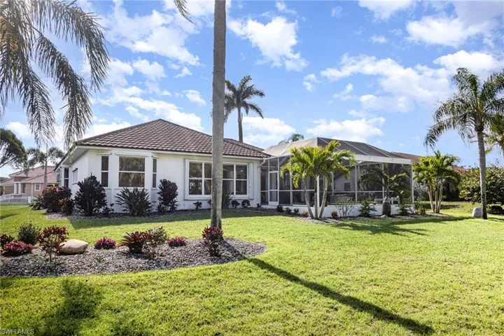 Back of property featuring glass enclosure and a lawn