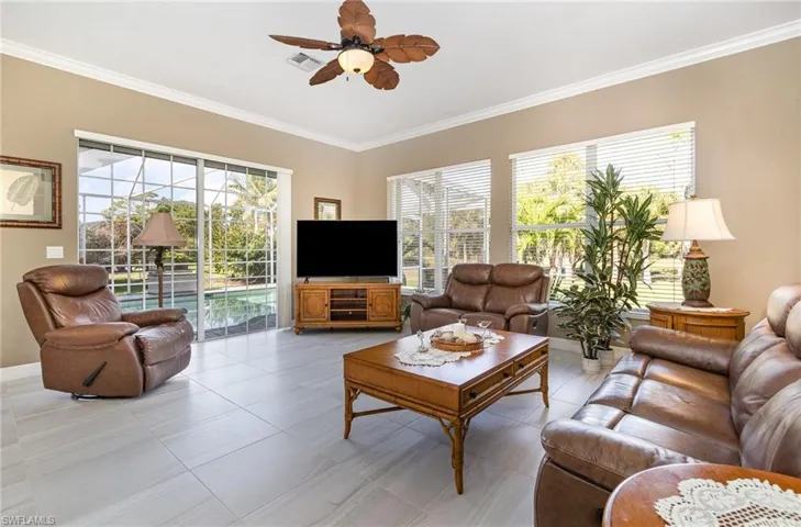 Living room featuring ceiling fan, crown molding, and tile flooring