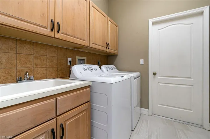 Washroom with sink, washer and clothes dryer, and cabinets