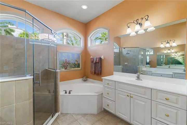 Master Bathroom #1 featuring Her vanity with sink and make up counter for her and his vanity with sink and drawers. deep Shower and tub. custom painted picture of the wall.